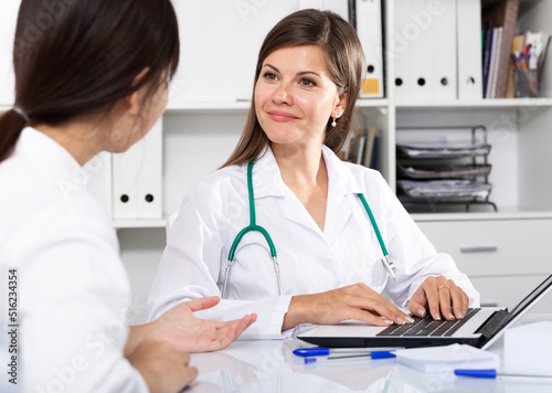 Young confident female doctor consulting woman patient in medical office