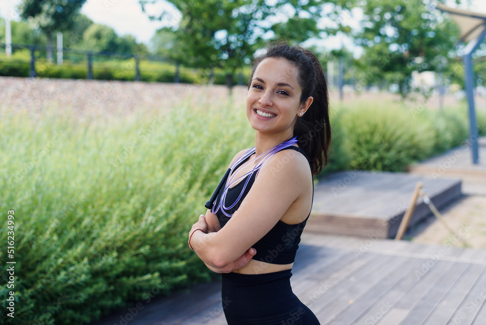 Portrait of fit young woman with jump rope in a park. Fitness female doing skipping workout outdoors on a sunny day. Portrait of fit young woman with jump rope in a park. Fitness female doing skipping workout outdoors on a sunny day.