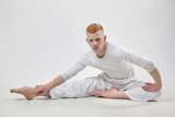 red-haired male dancer demonstrates the choreographic elements of the dance. photo shoot in the studio on a white background