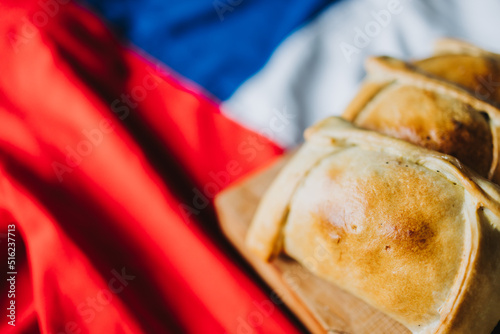 Baked meat chilean empanadas on the chilean flag. Copy space. Independence day concept. Selective focus photo