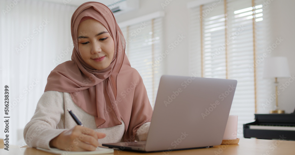 Young Gen Z workforce islam woman self learn MBA online class reskill upskill job at home. Asia people arab girl study relax sit at table wear hijab scarf write or typing e-mail work on digital laptop Young Gen Z workforce islam woman self learn MBA online class reskill upskill job at home. Asia people arab girl study relax sit at table wear hijab scarf write or typing e-mail work on digital laptop