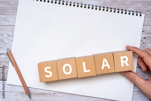 「SOLAR」と書かれたブロック、ノート、ペン、手 