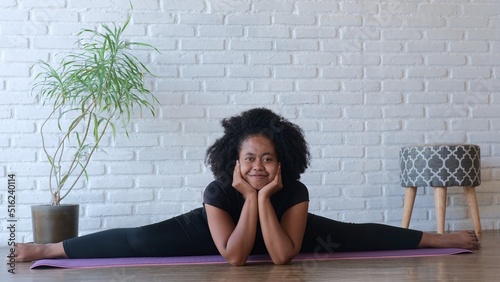 A swarthy woman sits on cross twine. Smiling. Strengthens the muscles in the hips, abdomen, back and buttocks by placing your hands in front of you and putting your chin on the palms of your hand.