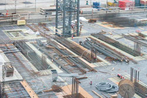 A large square footage of a commercial building with concrete forms, rebar, and electrical wires. The foundation of the skyrise building was built. The construction site has the base of a crane. photo