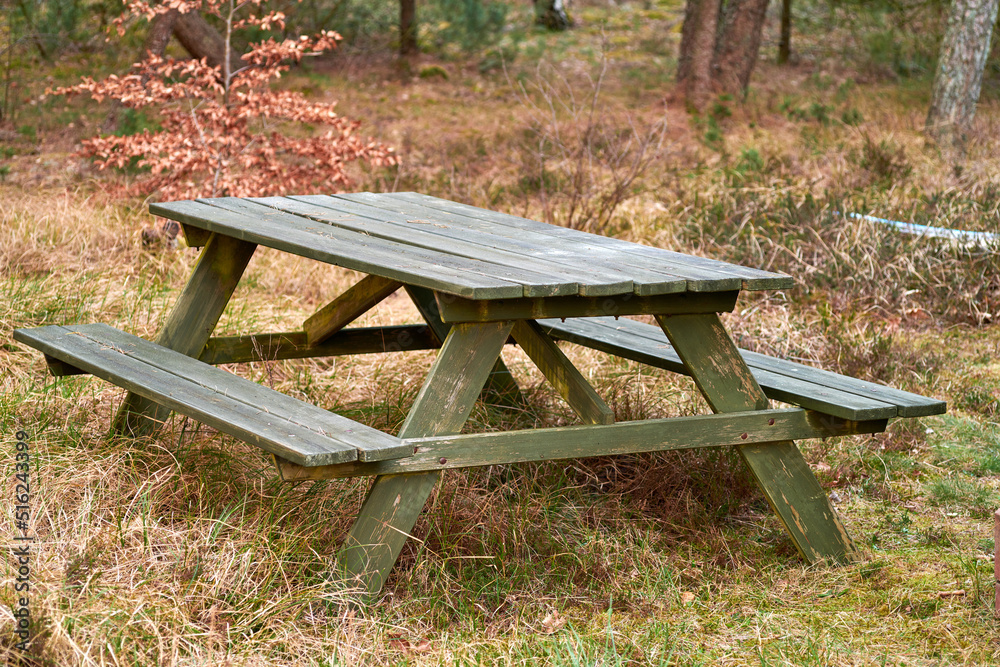 Wooden bench and table in a remote meadow for a picnic in the forest outside. Seating furniture in a park to enjoy a meal at while taking a break and rest from camping, hiking or exploring the woods Wooden bench and table in a remote meadow for a picnic in the forest outside. Seating furniture in a park to enjoy a meal at while taking a break and rest from camping, hiking or exploring the woods