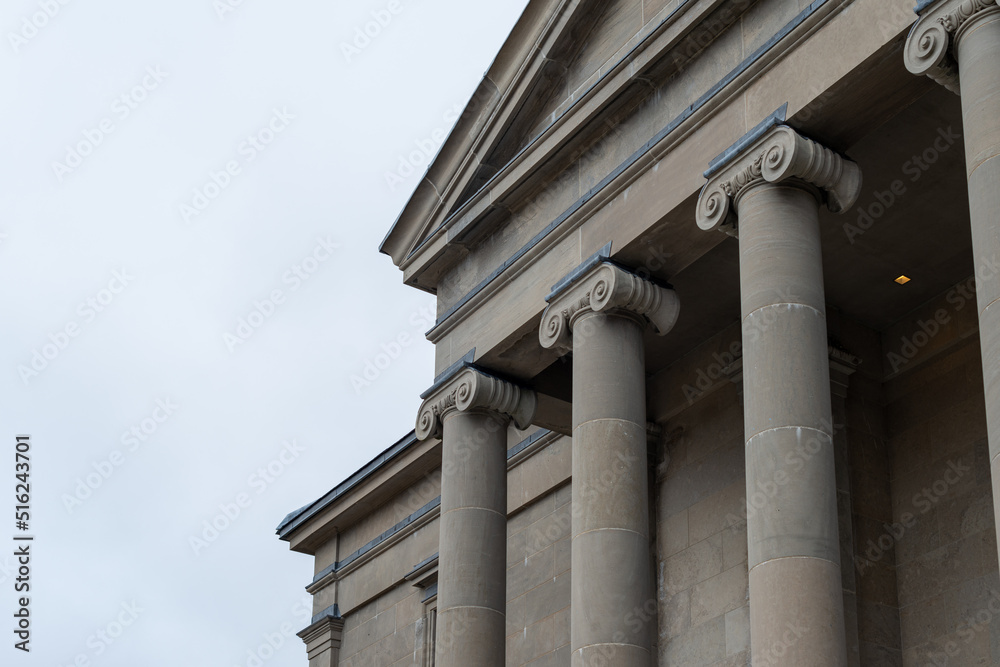 The exterior of a large courthouse with columns and pillars at the colonnade at the facade of the supreme justice government building. The exterior neoclassic structure is made of limestone blocks. The exterior of a large courthouse with columns and pillars at the colonnade at the facade of the supreme justice government building. The exterior neoclassic structure is made of limestone blocks.