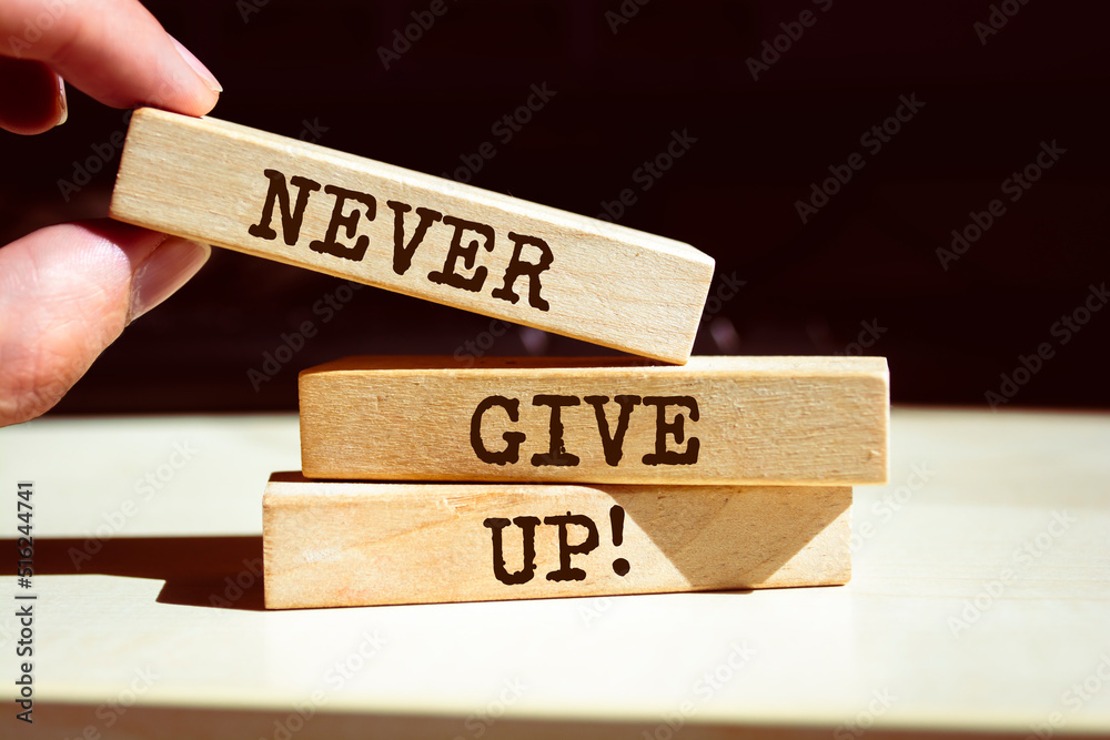 Never give up symbol. Businessman hand. Wooden blocks with words 'Never give up'. Never give up symbol. Businessman hand. Wooden blocks with words 'Never give up'.