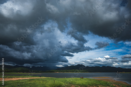 Stormy sky with cloud and dark environment above pond and lake surrounded with greenery and no people