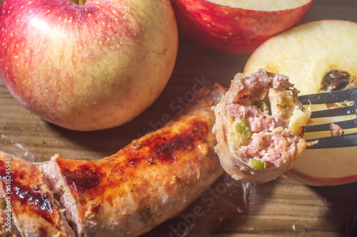 Sausage made with apple and jaalapeno pepper, on a wooden tablet with apples in the pictureand copy space photo