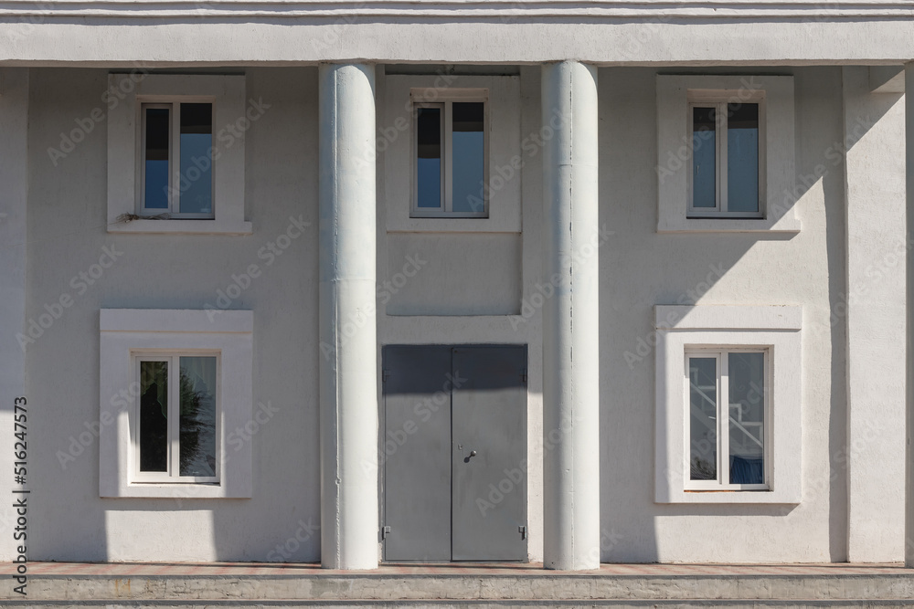 House wall texture with columns and windows with door on a summer sunny day