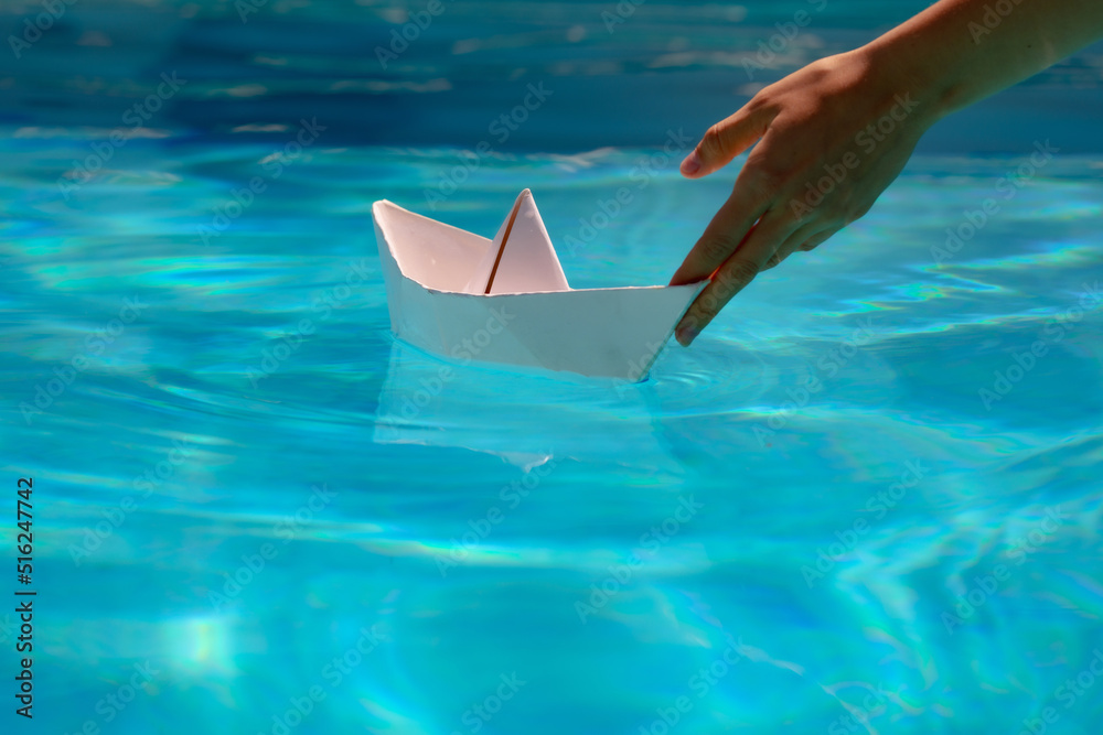 Paper ship in hand ready to sail. Tourism and traveling, travel dreams vacation holiday, sailing adventure. Hand holding paper boat on the sea background.