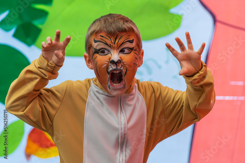 Lovely kid with paintings on his face and lion costume perform in a school festival 