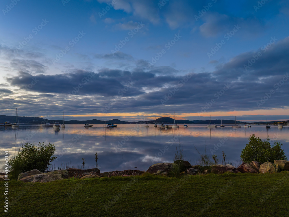 Obraz premium Aerial sunrise waterscape with boats, reflections and cloud filled sky
