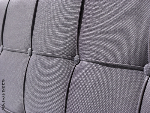 Gray color upholstered headboard close up , focus quilted headboard with button.