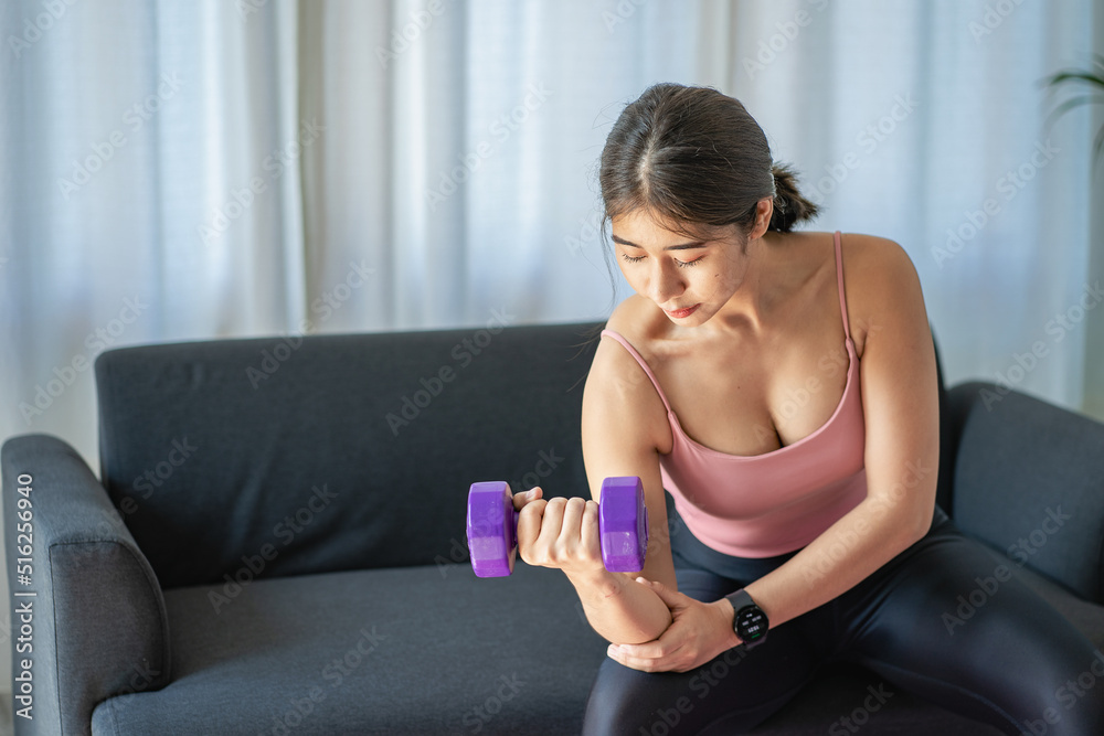A beautiful young Asian woman stretches her arms while watching online exercise exercises on laptop, young woman warming up yoga poses at home in living room. health care lifestyle good health concept A beautiful young Asian woman stretches her arms while watching online exercise exercises on laptop, young woman warming up yoga poses at home in living room. health care lifestyle good health concept
