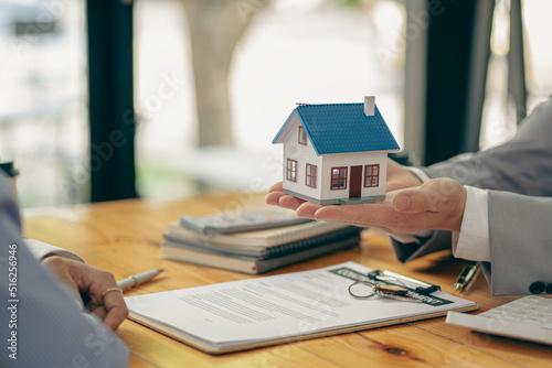 A real estate agent or bank officer explains the interest on a loan to customers with a home sales contract or office loan. Salesperson recommends insurance for customers who buy model homes.
