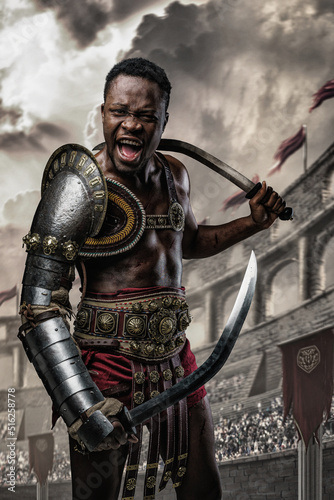 Shot of screaming african gladiator holding two swords in arena looking at camera.