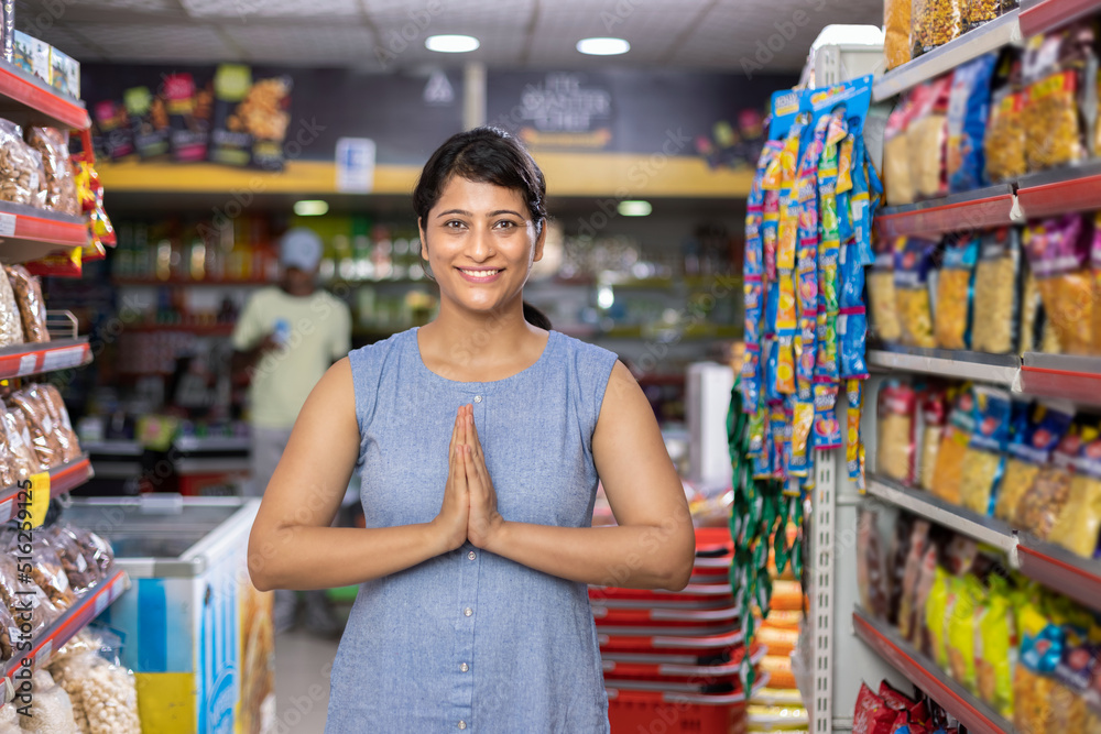 Portrait of an Indian woman greeting Namaste at grocery aisle of supermarket
