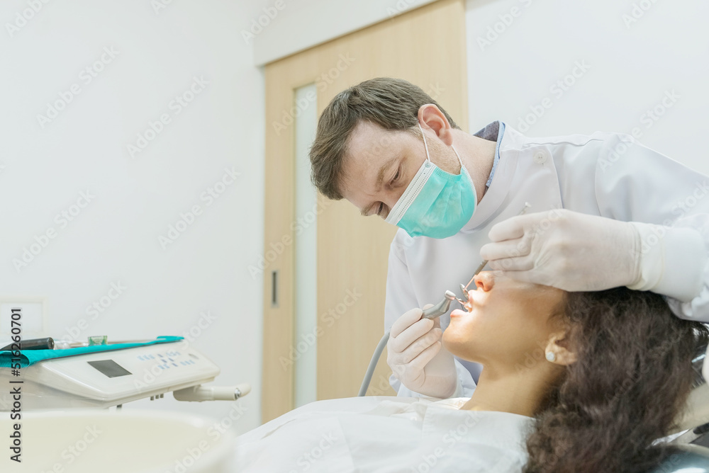 Caucasian male dentist examining young girl patient teeth at dental clinic. Caucasian male dentist examining young girl patient teeth at dental clinic.