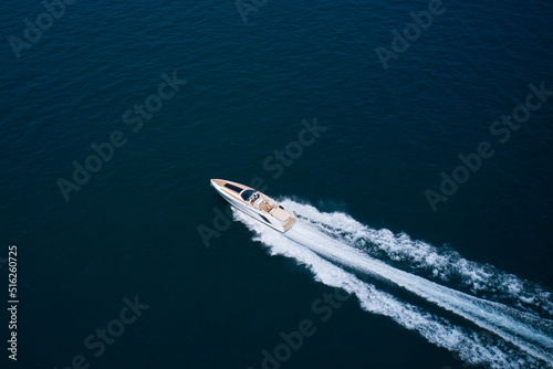 Expensive big open super high speed white boat with people moving on water top view. Speedy white boat movement on dark water aerial view. © Berg