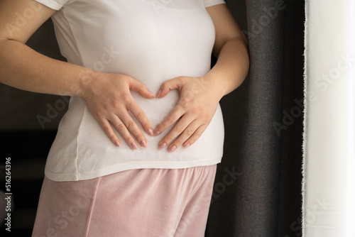 Beautiful young pregnant woman making a heart with her hands, pregnant woman's belly with fingers heart symbol