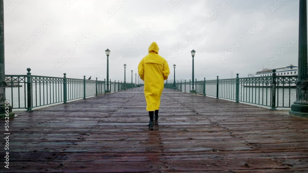 Fascinating vista of San Francisco covered in a misty fog. Low angle shot of a lonely tourist in a yellow raincoat strolling at pier. High quality 4k footage Fascinating vista of San Francisco covered in a misty fog. Low angle shot of a lonely tourist in a yellow raincoat strolling at pier. High quality 4k footage