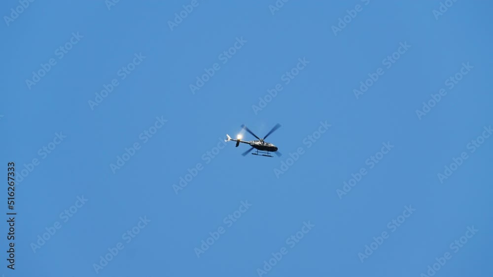 Bottom Up View of a Helicopter Hovers Up High in the Blue Sky on a Bright Day Bottom Up View of a Helicopter Hovers Up High in the Blue Sky on a Bright Day