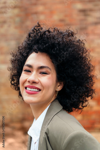 portrait of a young latin woman with curly hair smiling looking at the camera, concept of youth and happiness, copy space for text