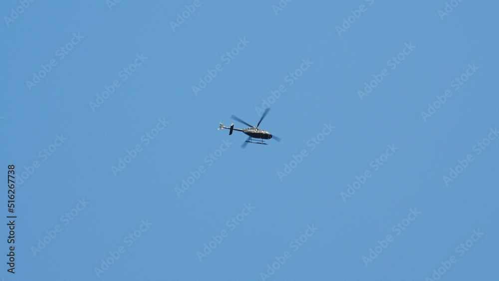 Bottom Up View of a Helicopter Hovers Up High in the Blue Sky on a Bright Day Bottom Up View of a Helicopter Hovers Up High in the Blue Sky on a Bright Day
