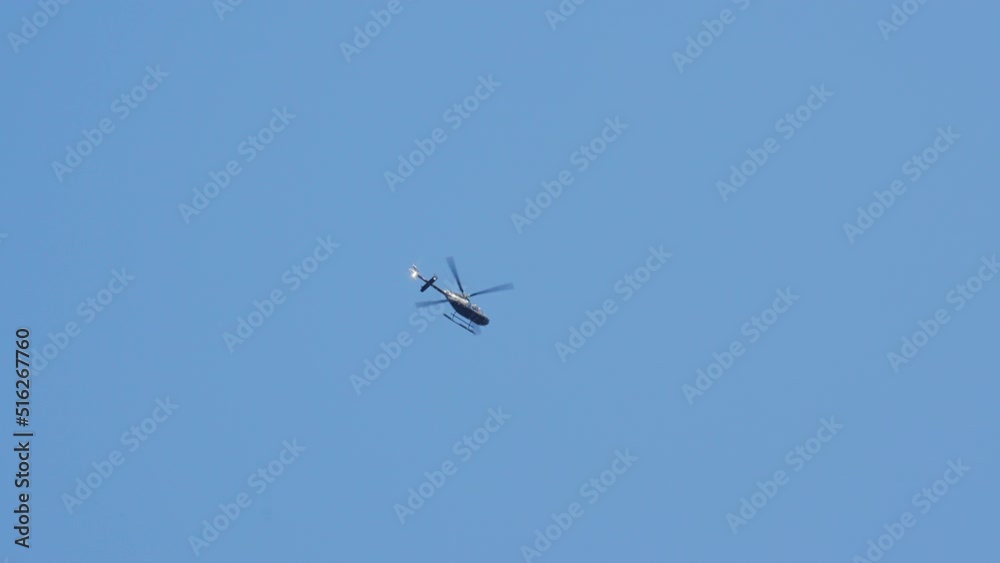 Bottom Up View of a Helicopter Hovers Up High in the Blue Sky on a Bright Day Bottom Up View of a Helicopter Hovers Up High in the Blue Sky on a Bright Day