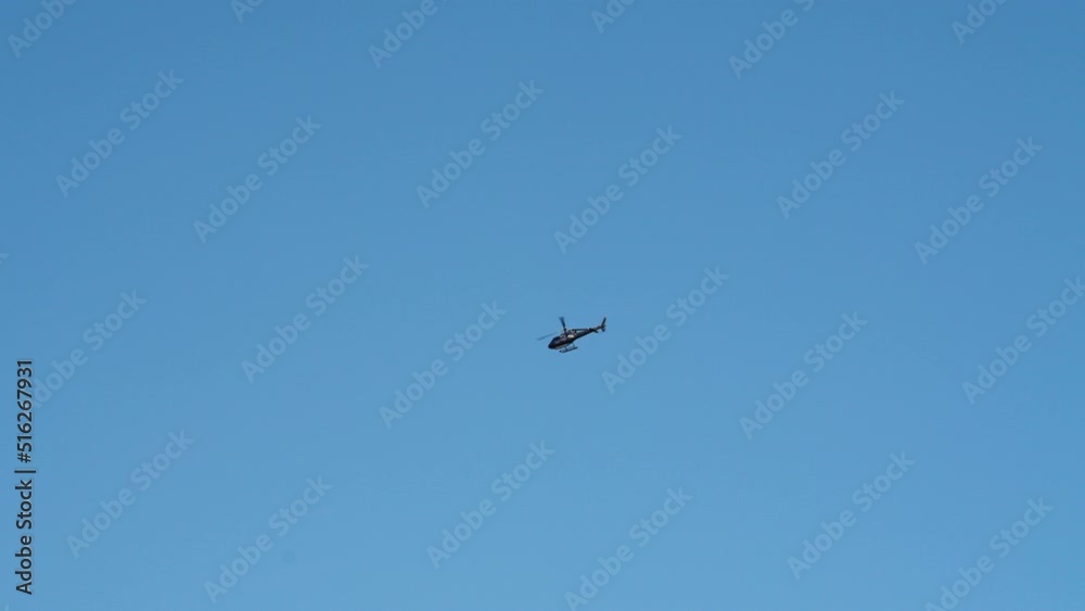 Wide Bottom Up View of a Helicopter Flies Through the Blue Sky on a Bright Day Wide Bottom Up View of a Helicopter Flies Through the Blue Sky on a Bright Day