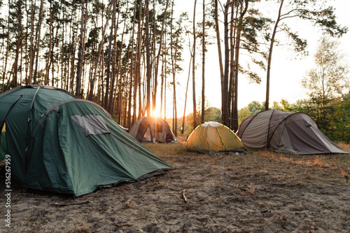 summer camp in the forest. dawn in the forest against the background of a group of tents. wonderful summer vacation in the forest. people sleep in tents © Vadym