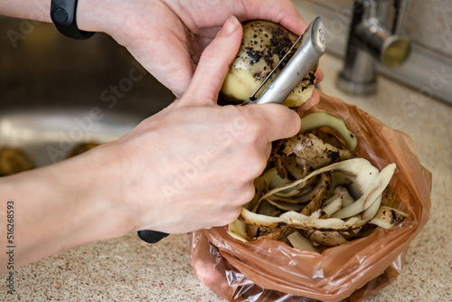 Food waste. Close-up female hands of a cook peel raw potatoes for cooking a dish.Potato peelings.