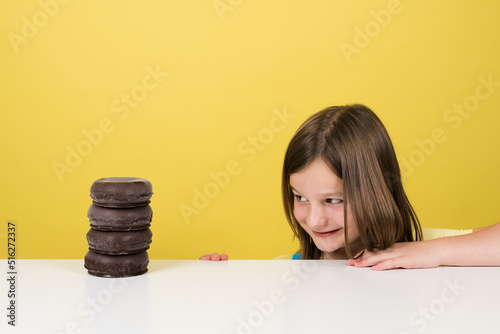 Print op canvas Little girl looking with envy at pile of donut