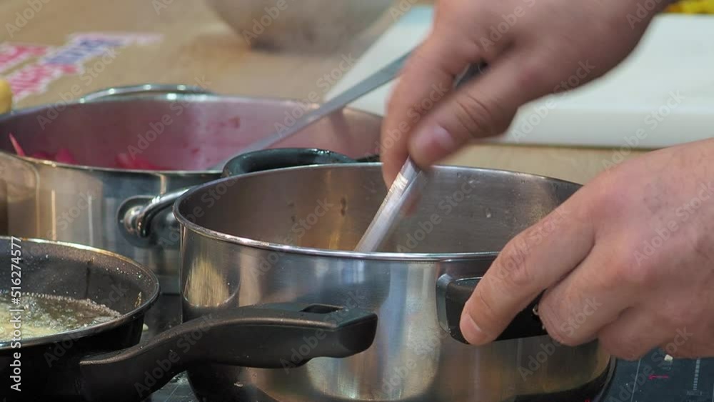 Close up gimbal shot of hands stirring food in pot with fork Close up gimbal shot of hands stirring food in pot with fork