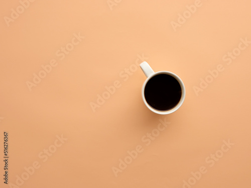 Coffee mug with black coffee on salmon colored background