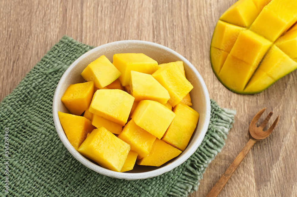 A bowl of sliced fresh mango cubes on wooden background. Copy space
A bowl of sliced fresh mango cubes on wooden background. Copy space