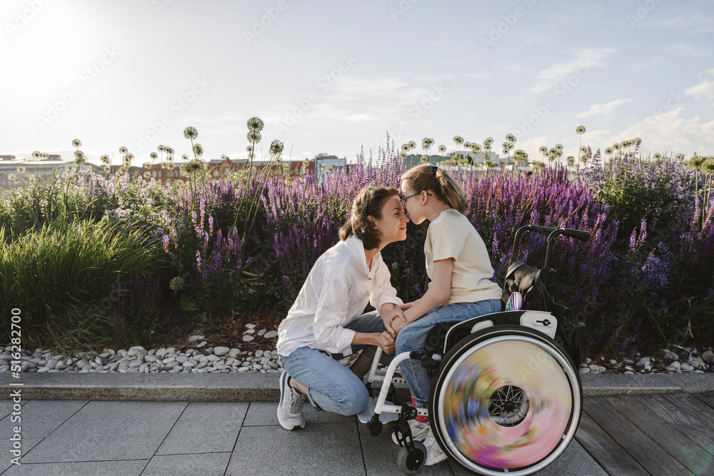 Daughter in wheelchair kissing mother at park Stock Photo Adobe Stock