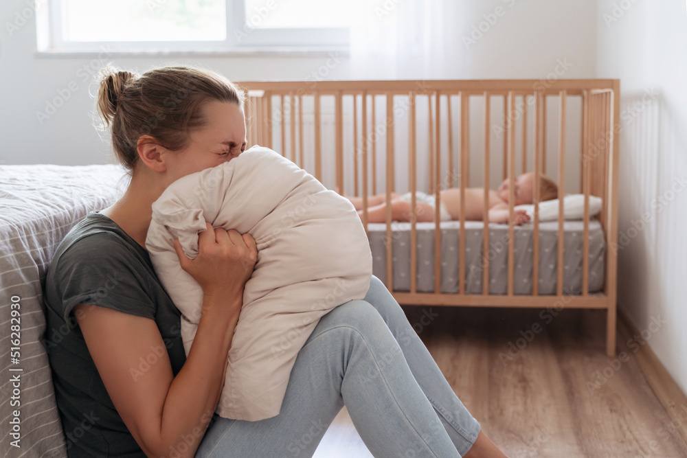 Depressed mother screaming with anger and desperation in pillow to