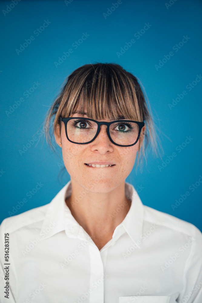 Businesswoman biting lip against blue background Businesswoman biting lip against blue background