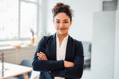 Smiling businesswoman with arms crossed standing in office photo