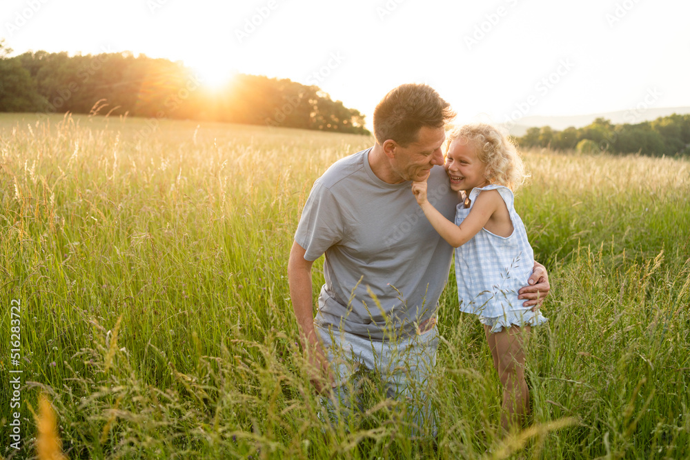 Happy girl standing by father kneeling on grass at field Happy girl standing by father kneeling on grass at field
