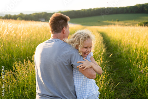 Cheerful daughter enjoying with father at field on sunny day photo