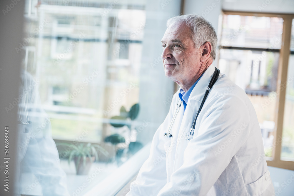 Smiling doctor looking through window at hospital Smiling doctor looking through window at hospital