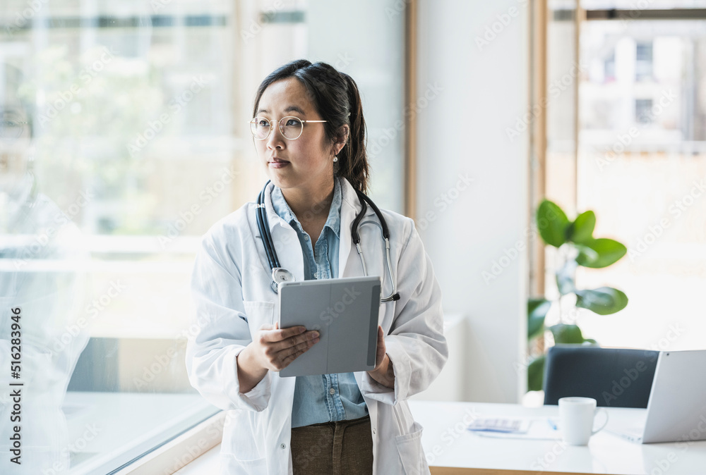 Female doctor with tablet PC standing in office Female doctor with tablet PC standing in office