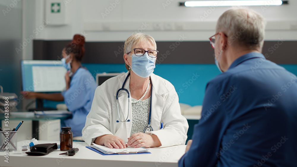 Obraz premium Female medic consulting retired sick patient in medical cabinet, attending examination appointment at health care center. Checkup visit consultation with diagnosis treatment during pandemic.