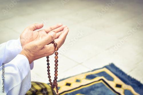 Muslim man in white session lift two hand for praying and wearing bead on hand to determine the number of prayer services.concept for Ramadan, Eid al Fitr, eid ad-ha, meditation, islamic praying