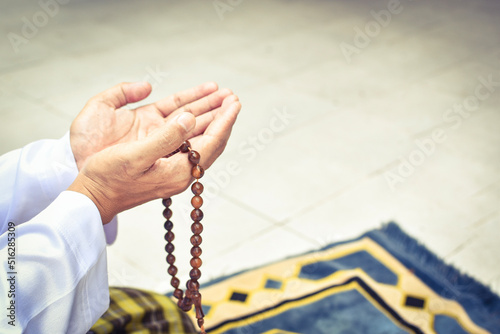 Muslim man in white session lift two hand for praying and wearing bead on hand to determine the number of prayer services.concept for Ramadan, Eid al Fitr, eid ad-ha, meditation, islamic praying photo