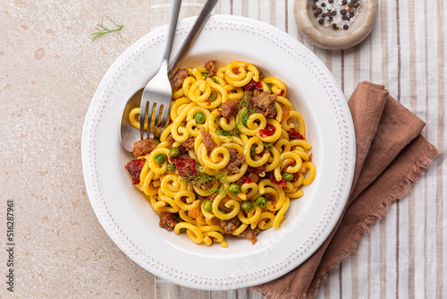 Italian meat pasta Gramigna with salsiccia, green peas and sun dried tomatoes. Directly above. photo