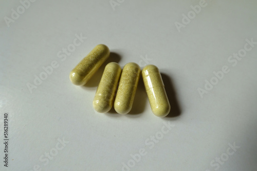 Group of four yellowish green capsules of quercetin dietary supplement photo